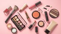 Lipstick, nail polish, blush and other cosmetics from above on a pink background
